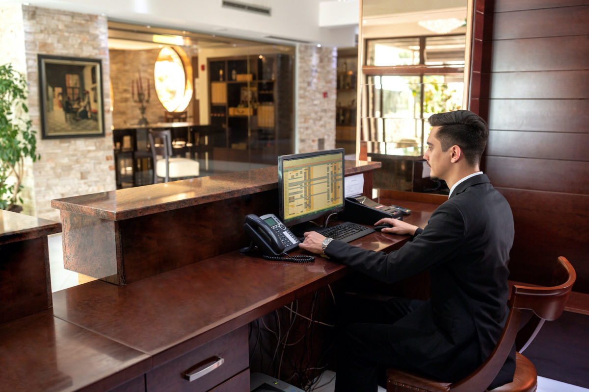 A young man working at the front desk of a hotel by allegiance staffing a leading staffing agency in houston, texas.