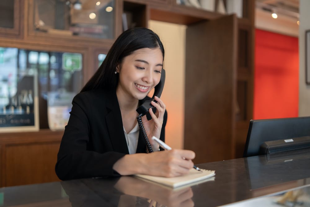 Young woman working at a hotel front desk by allegiance staffing