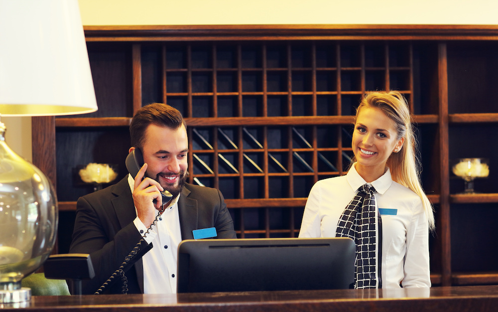 Young man and woman working the front desk at a hotel