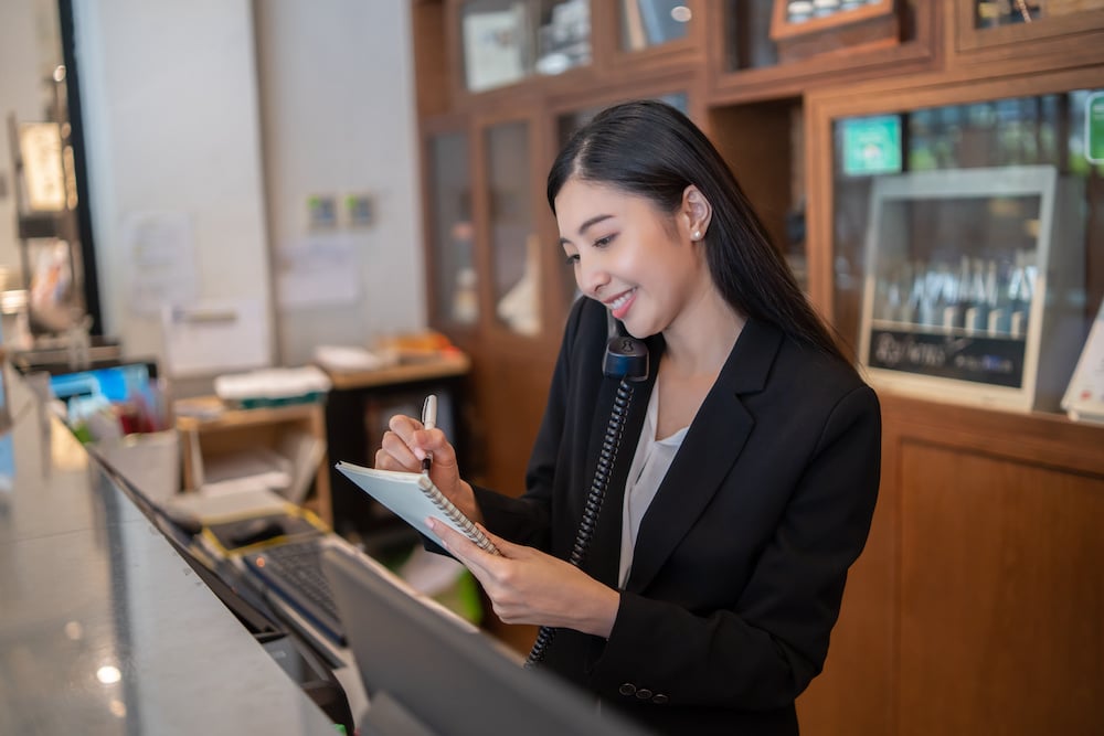 Professional juggling tasks at hotel front desk after finding out more about whether working at a hotel is stressful