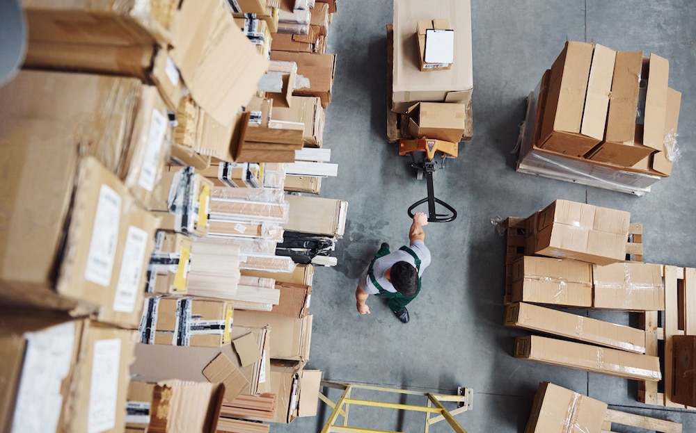 Man working in a warehouse moving boxes after looking through warehouse jobs that hire felons