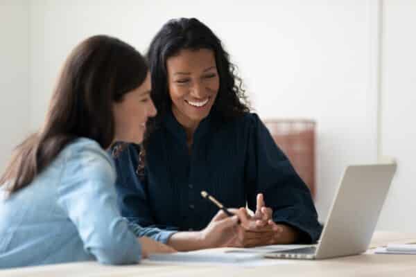 Female worker receiving support from a mentor in a meeting space
