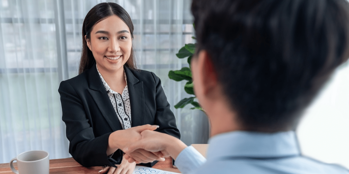 Professional shaking hands with an employer after being placed in a permanent role