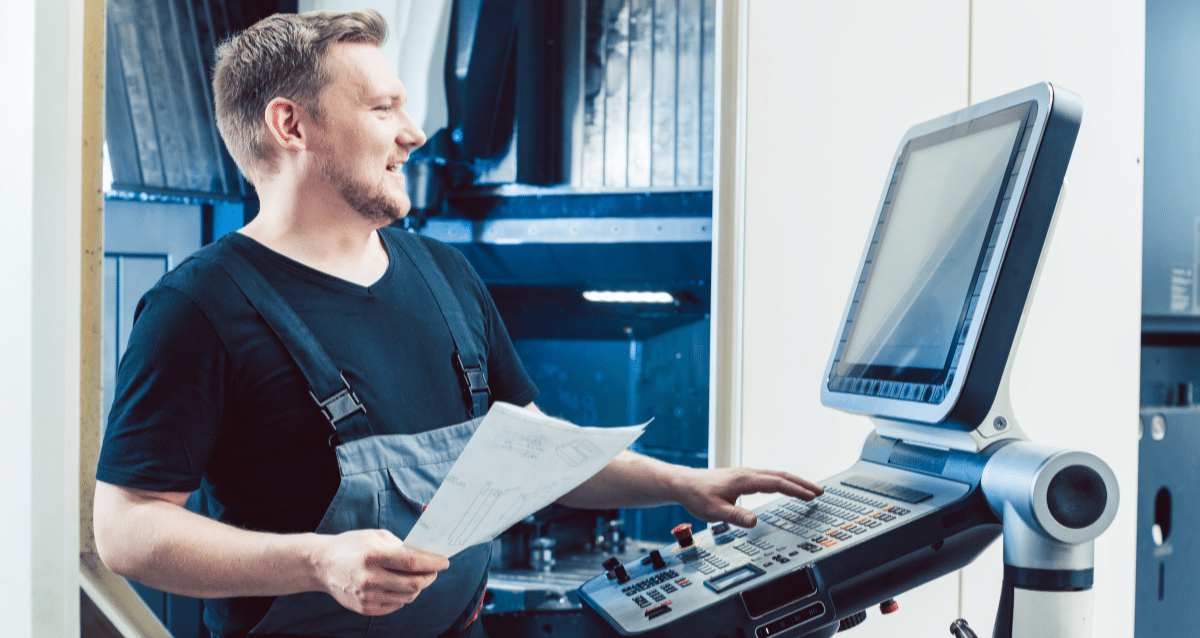 Worker operating a CNC machine in an industrial setting
