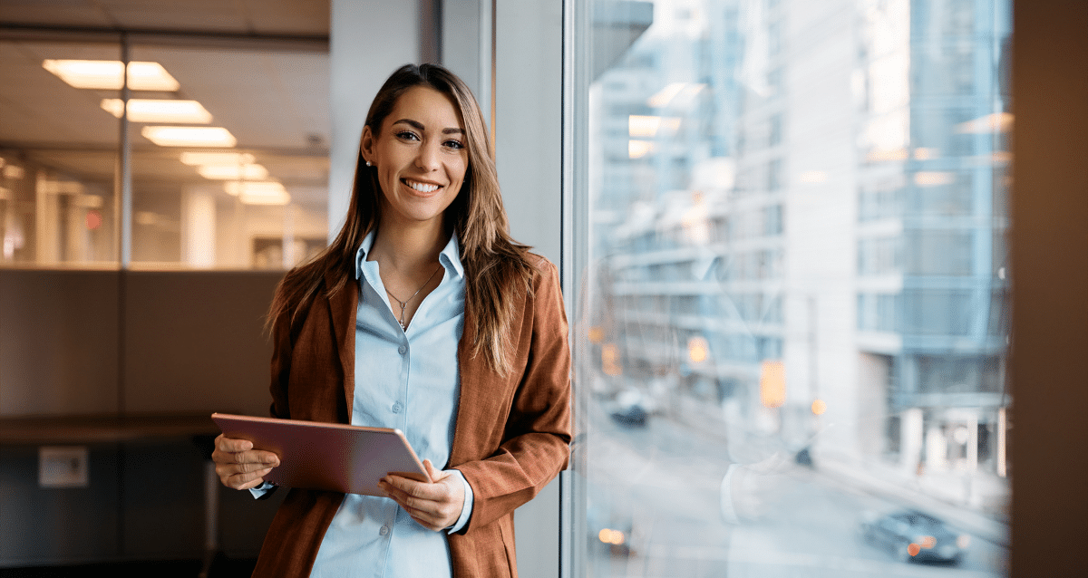 Smiling office manager holding a tablet in an office clerical setting